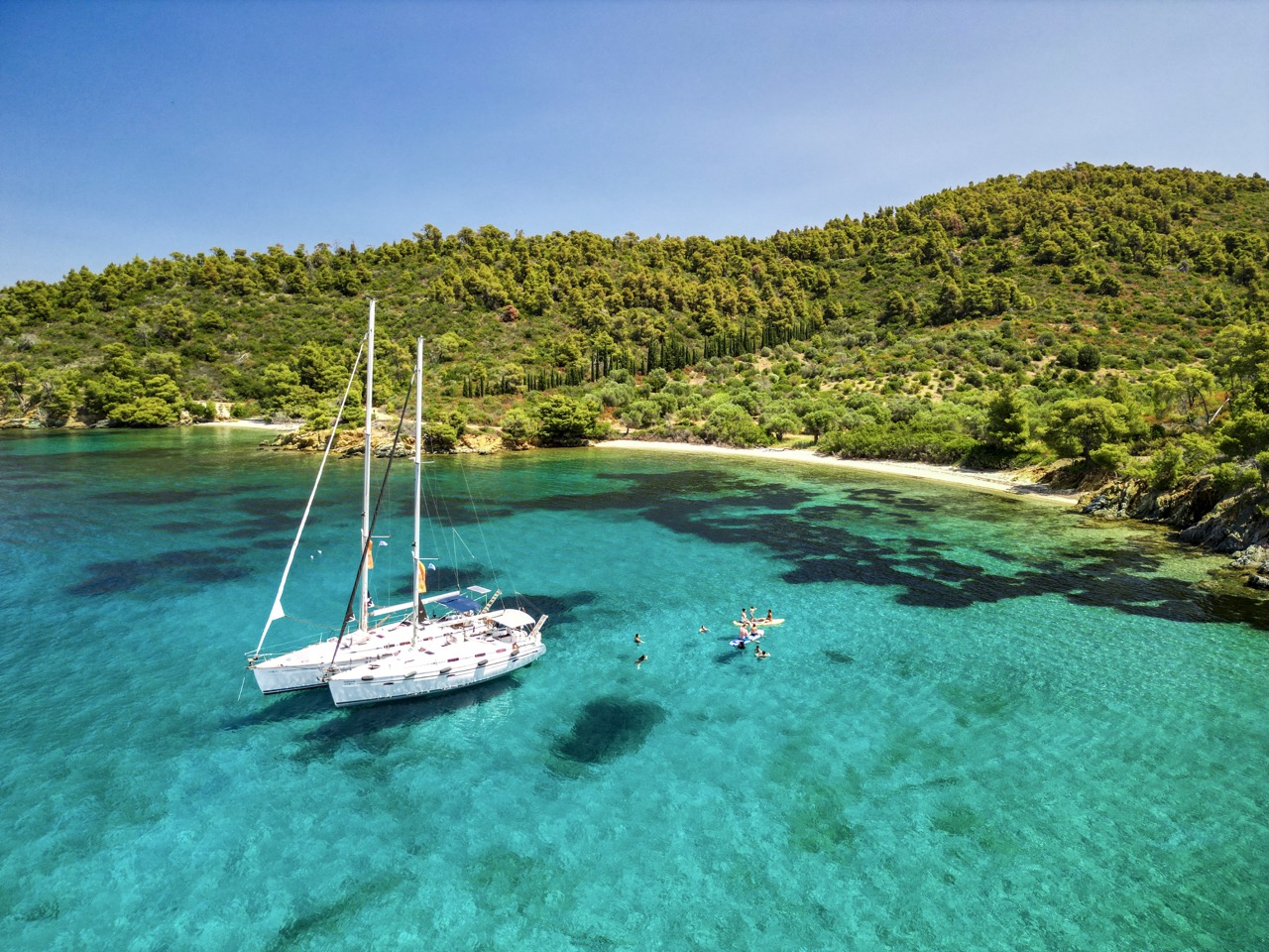 Sailing Sithonia — two sailing yachts anchored in turquoise waters surrounded by pine forest, Halkidiki